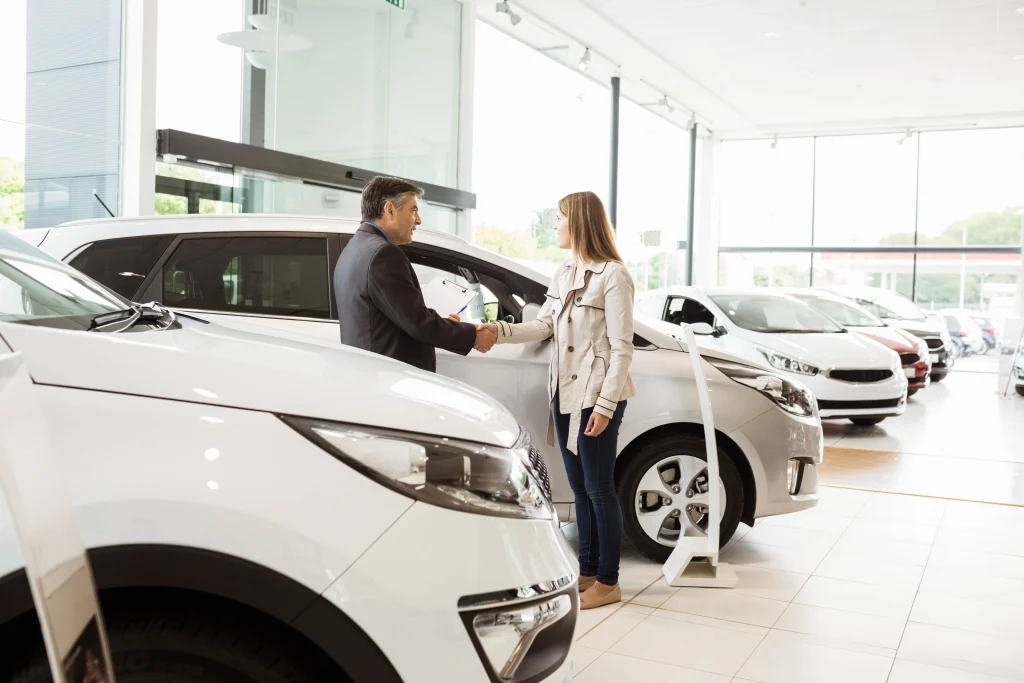 A car salesman shakes hands with a new customer.