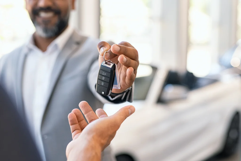 Car salesman hands keys to new customer.