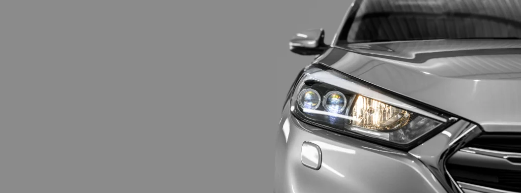 A new silver car is parked at a dealership showroom.